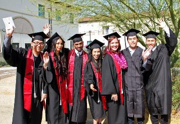 waving students in caps and gowns